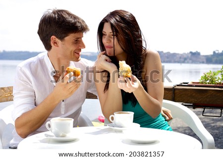 Happy couple eating cake in hotel in front of lake in Italy
