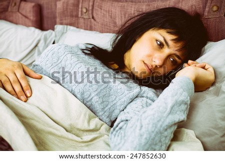 Unhappy young woman thinking in bed