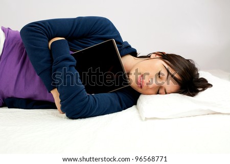 Young woman sleeping happy with tablet computer in her arms