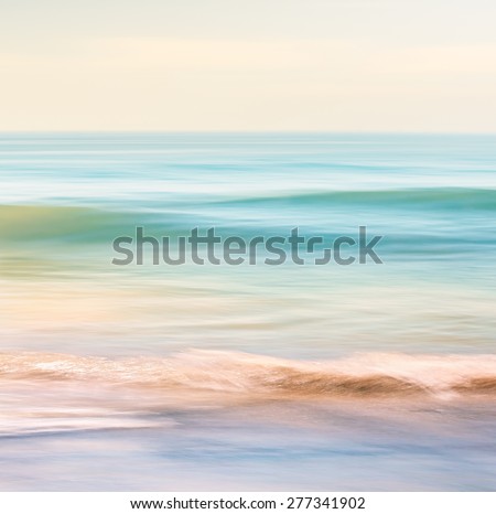 A high-key seascape featuring ocean waves with blurred panning motion.  Image displays subtle cross-processing and light, pastel colors.