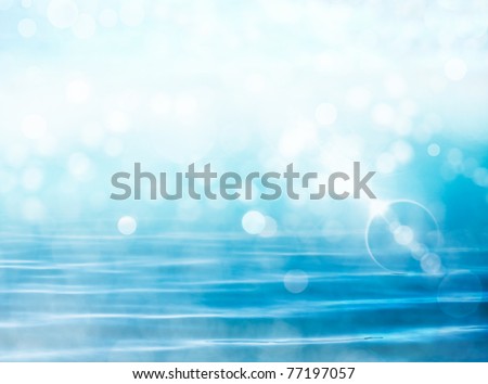 Soft focus bokeh light effects over a rippled, blue water background with  lens flare.