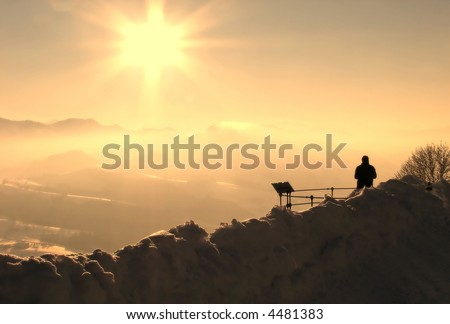 Silhouette of a man in a winter landscape looking at the mountains in the distance