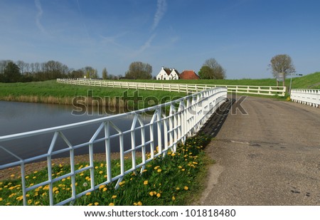 White fence leading towards an old, white farmhouse in Holland.