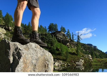 Hiker and his hiking boots standing on a boulder in the mountains.