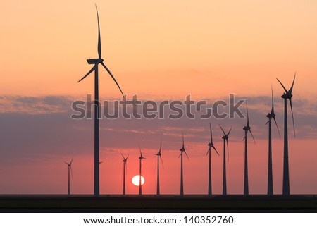 Modern wind turbines near the Eemshaven (the Netherlands) producing clean energy during a nice sunset.