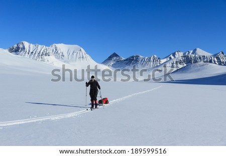 Female cross country skier with polka (sled) in the snow in Lapland, Sweden.