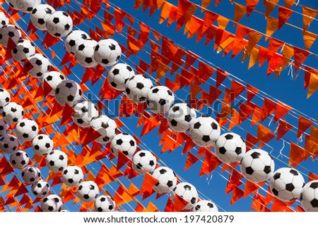 Orange flags (Dutch national color), footballs and a blue sky during the world soccer cup of 2014.