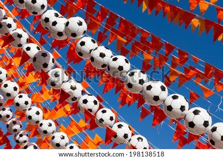Orange flags (Dutch national color) and footballs against a clear, blue sky during world soccer cup of 2014.