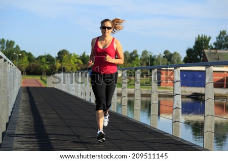 Healthy lifestyle sports concept: woman running on a boardwalk at a lake on a sunny morning.