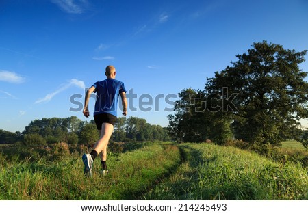 Man trail running in the countryside on a sunny morning.