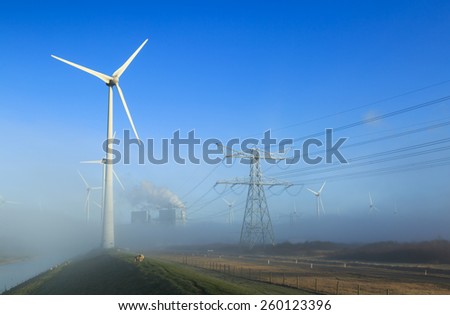 Wind turbines generating sustainable energy on a foggy morning in an industrial area.