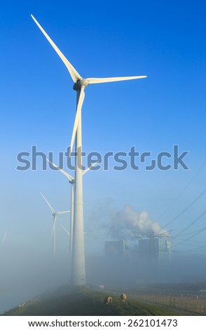 Wind turbines generating sustainable energy on a foggy morning in an industrial area.