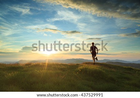 Athlete trail running in the mountains during a nice sunset. Shallow D.O.F. and with motion blur.