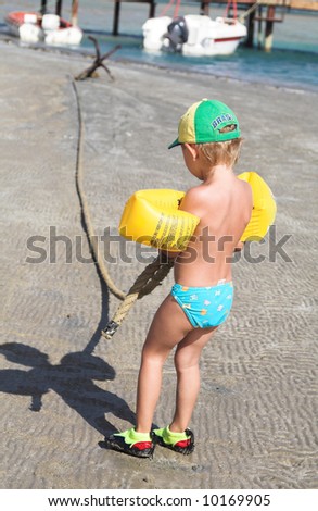 The boy pulls an anchor rope on sand