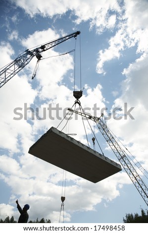 Hoisting crane lifts heavy concrete grey slab