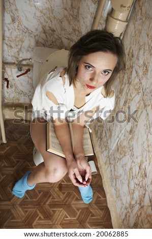 stock photo Young girl reading book in toilet