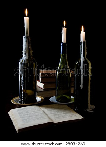 Three candles and books on black background