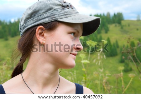 Young woman in a denim cap looks in the side