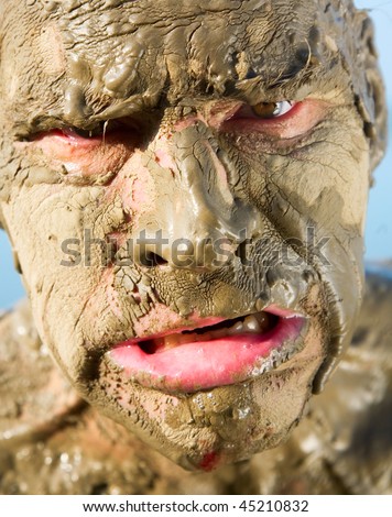 man\'s face is very dirty in the mud. Dirt is not curative