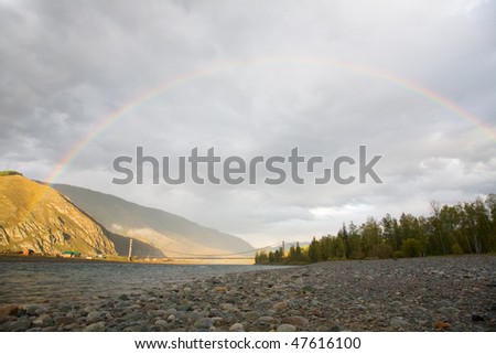 Rainbow over the mountain river after the rain