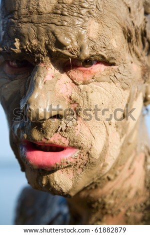 Man\'s face is very dirty in the mud. Dirt is not curative