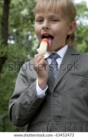 boy in a gray suit eats ice cream in the park