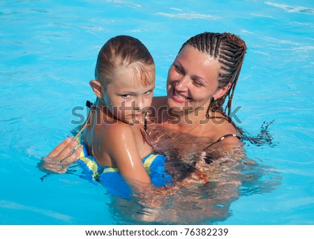 Mother and son have fun swimming in the pool with turquoise water