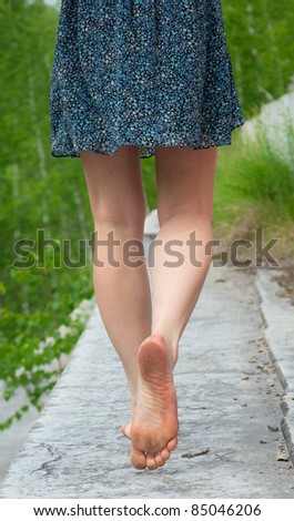 A young woman goes barefoot on the stone parapet