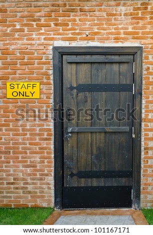Staff only room with brick wall and old retro interior entrance door design - do not enter without authorization warning badge label