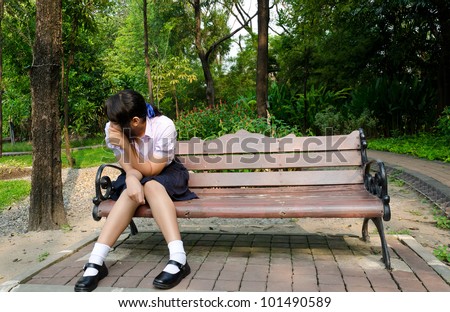 Thai high-school student crying alone on the bench in the park.