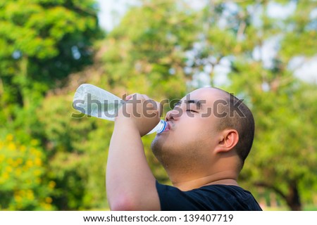 An Asian bald head guy is drinking water with thirst