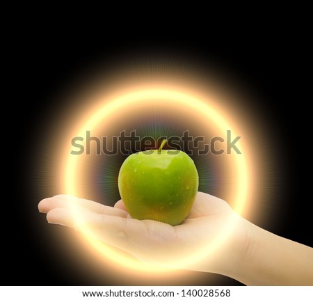 Magic apple on man or woman palm hand with magical light power in circle shape in black isolated background. It is a super magical nutritious food source of vitamin, fiber, and nutrition anti aging.
