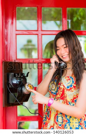 Thai girl is talking with an old-fashion phone in the telephone booth