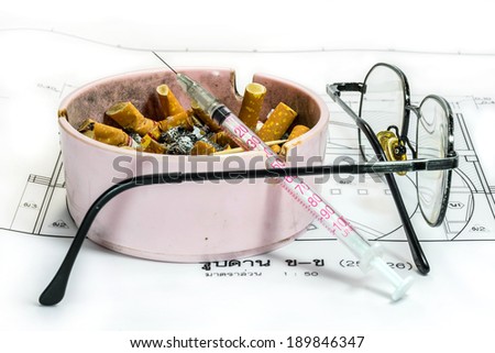 Ashtray, syringe, and glasses white Thai language blueprint background representing stress in work concept. The Thai word on the paper means scale 1:50