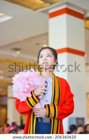 Bright Thai college girl in academic gown is looking forward to the future in her graduation day