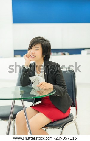 Cute Thai (Asian) businesswoman sitting in the office with a smiling welcome