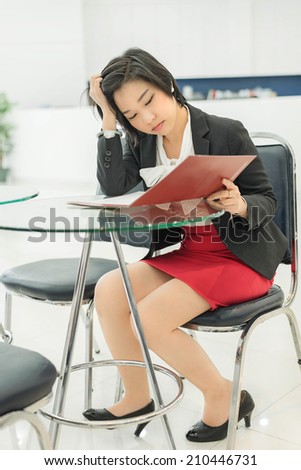 Stress Thai (Asian) businesswoman is reading her document file in office as work