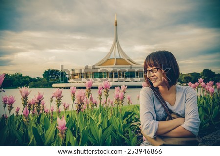 Cute Thai girl is relaxing beside the river bank, near a Siam Tulip field in vintage concept