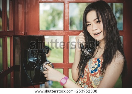 Thai girl is talking with an old-fashion phone in the telephone booth  in retro color style