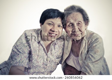 Family Portrait of an Asian elder mother and daughter hugging in isolated background in retro color