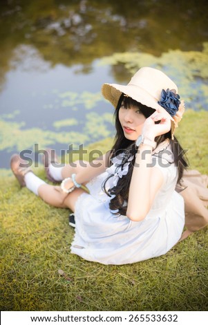 A cute Asian Thai girl is relaxing near the pond in the wilderness