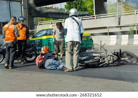 BANGKOK, THAILAND - APRIL 28: Motorcycle accidents on the street of Bangkok due to road slippery on April 28, 2012. People around that area gather to help the injury.