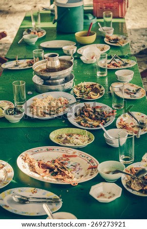 Remaining plates leftover on the table with remaining Thai food in vintage color