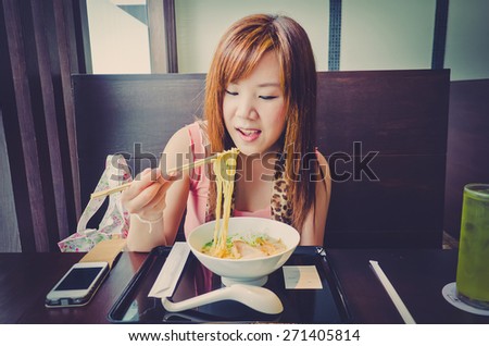 A cute Thai girl is eating a Japanese Ramen in the resturant in vintage color. This is urban life.