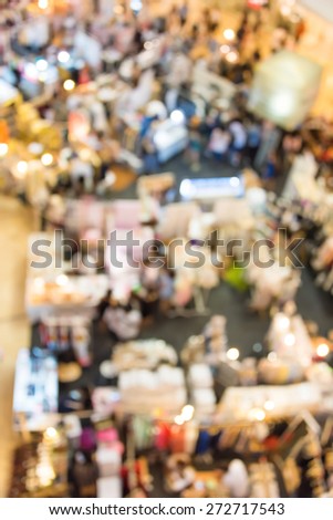Blur background photograph of the ground floor with people and booths in an indoor building, shoot from above in top view.