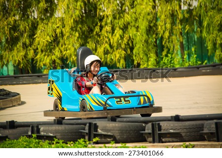 Cute Asian Thai girl is driving Go-kart car with speed in a playground racing track. Go kart is a popular leisure motor sports.