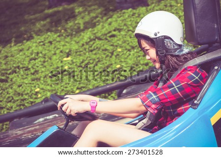 Cute Asian Thai teen girl is driving Go-kart car in playground with speed in retro color