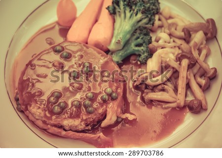 Filet Mignon steak with gravy sauce and carrot broccoli mushroom side-dish on dish in vintage color. It\'s a international French cuisine food