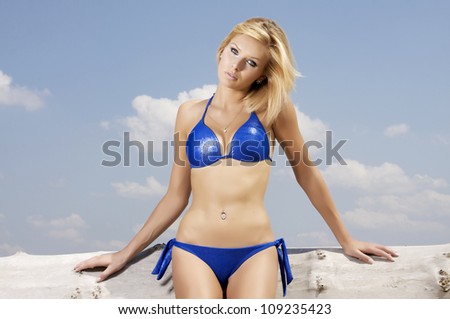 beautiful blonde woman in white blue posing on a log