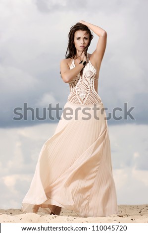 Fashionable young attractive and sensuality brunette woman in white dress dancing on the desert